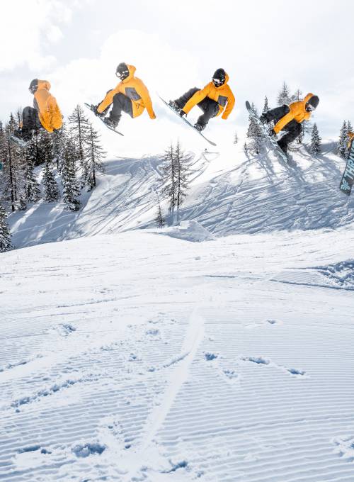 Ein Mann übt Ski-Tricks direkt neben der Piste beim Alpina Family, Spa & Sporthotel. 