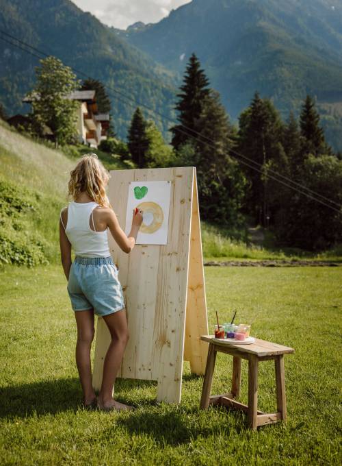 Ein Mädchen malt ein Bild in der Kinderbetreung im Alpina Alpendorf.