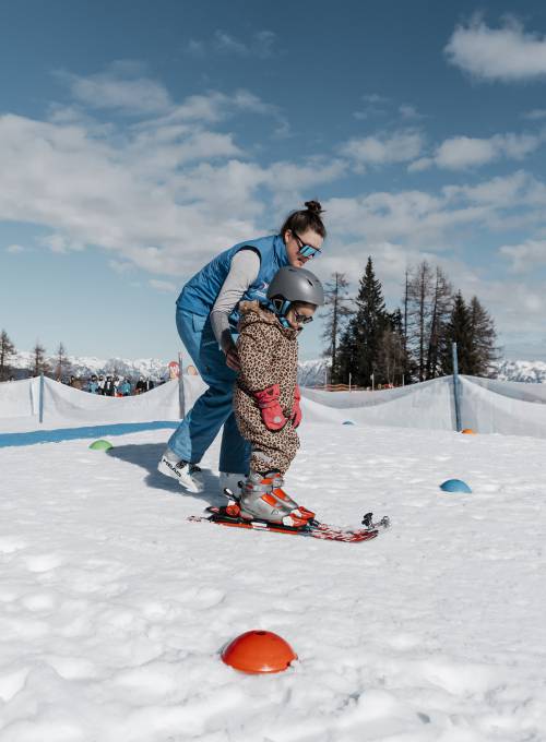 Ein Mädchen hat die ersten Erfolge beim Skifahren in der Kinder-Skischule im Alpendorf. 