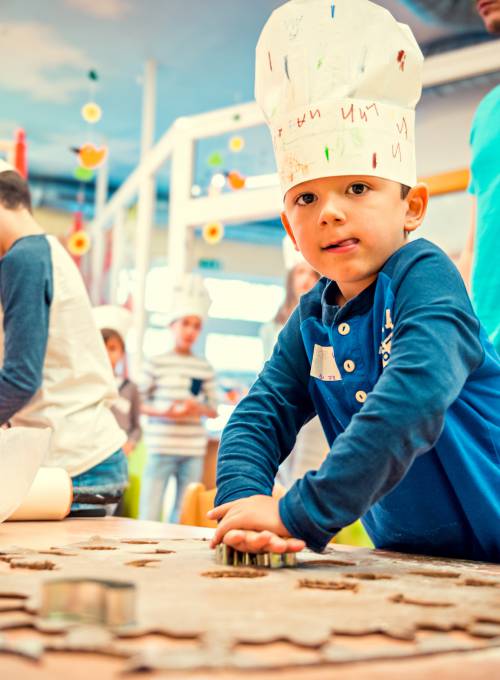 In unserem Hotel mit Kinderbetreuung in Österreich backt ein Kind Kekse.