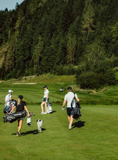Eine Familie bei der Platzrunde während des Golfurlaubs im Salzburgerland. 