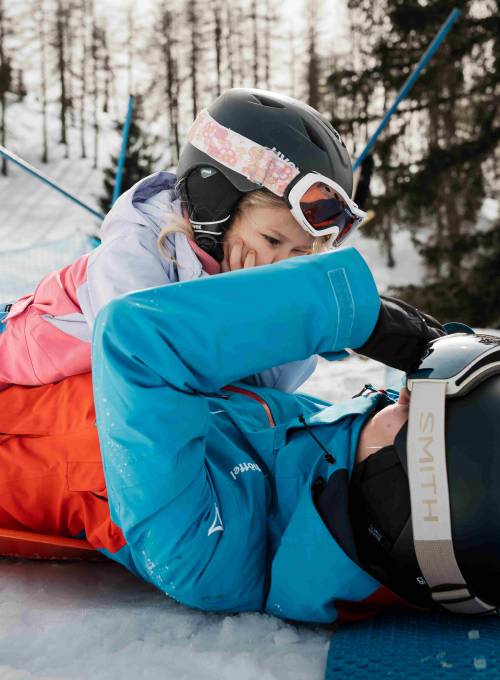 Ein Kind spielt mir ihrer Skilehrerin im Schnee im Skigebiet Snow Space.