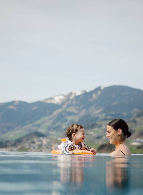 Ein Baby bekommt die 1. Schwimmstunde in Alpinas outdoor Pool im Sommer. 